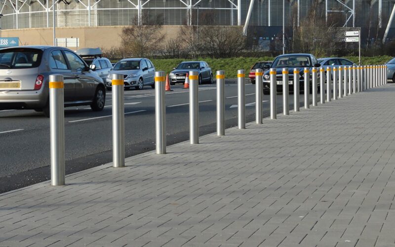 crash tested bollards on a street with cars driving by