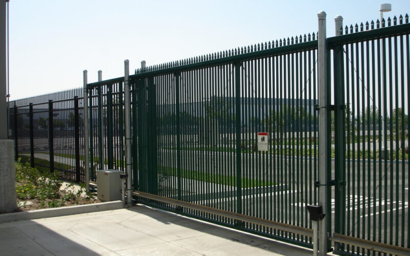 wrought iron perimeter security fencing in a dark metallic finish with blue sky and warm sunlight in the background