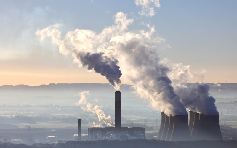 An aerial view of a thermal power station with the sunrise and mountains in the background