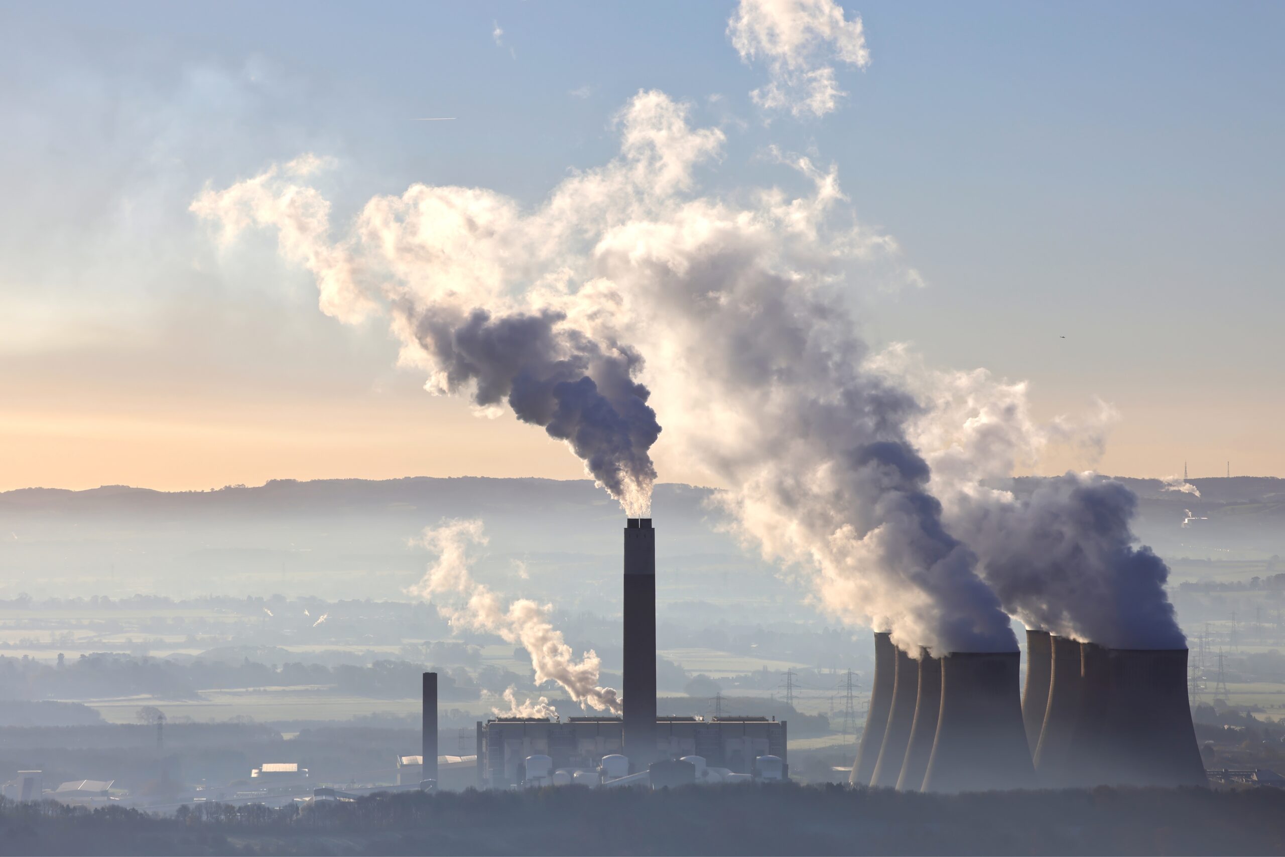 An aerial view of a thermal power station with the sunrise and mountains in the background