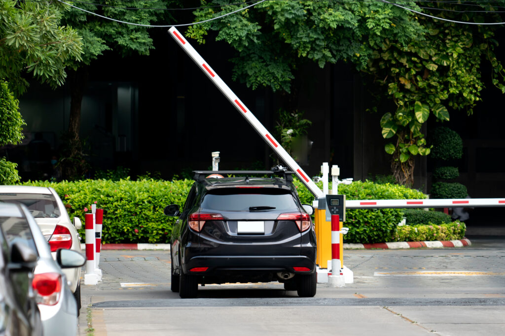 A car prepares to drive through a security gate to enter a parking lot for a business with robust business security solutions
