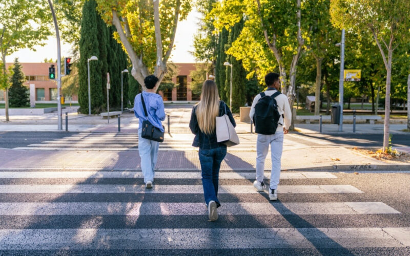 A group of college students cross a walkway on their school campus,