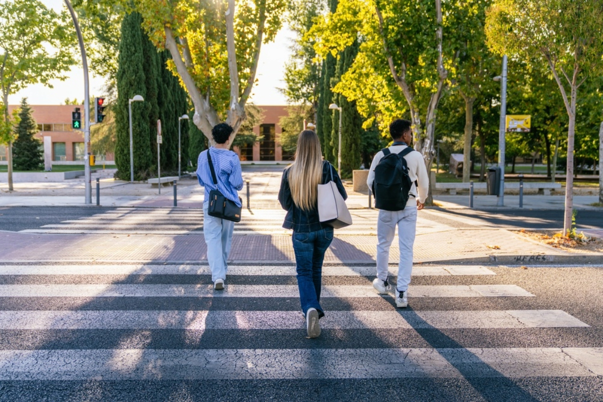 A group of college students cross a walkway on their school campus,